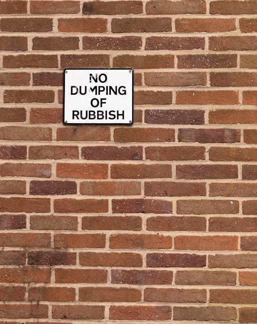 A rectangular metal sign mounted on a red-brown brick wall, displaying the message